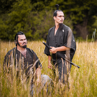 Step into the ancient world of Japanese legend as Minamoto no Yorimitsu and Watanabe no Tsuna, portrayed by Anett Alexandra Bulano, stand resolute in the face of supernatural terror. Their noble presence, captured against a backdrop of golden wheat fields, echoes the valor and honor of samurai tradition. Inspired by the Tsuchigumo SΕshi folktale, this depiction pays homage to the bravery of these legendary figures. An image showing Minamoto no Yorimitsu and Watanabe no Tsuna, two Japanese samurai, standing in a wheat field. Both are adorned in traditional Japanese attire and hairstyles, created by makeup artist Anett Alexandra Bulano to reflect the characters from the Tsuchigumo SΕshi folktale.